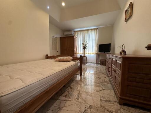 Spacious bedroom with light marble flooring and wooden furniture