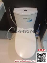 Modern white ceramic toilet in a bathroom with a visible toilet brush