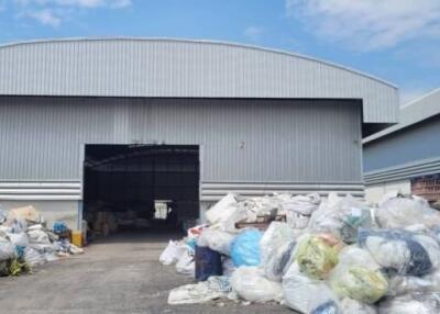 Large industrial warehouse with open bay door and surrounding waste material