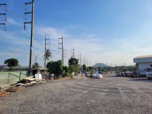 Vast outdoor space with power lines and industrial buildings under a clear sky