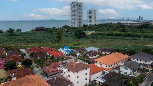 Aerial view of a residential neighborhood with proximity to the coastline and urban skyline in the distance