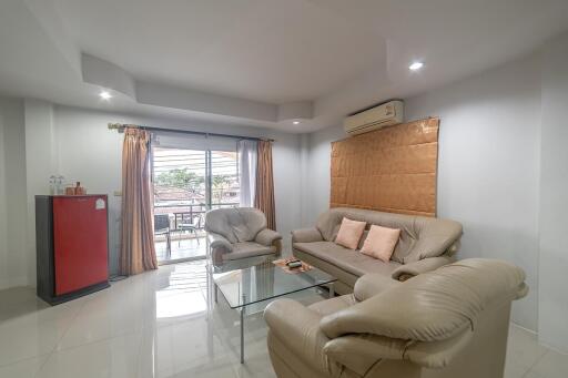 Spacious and well-lit living room with comfortable seating and glass-top coffee table