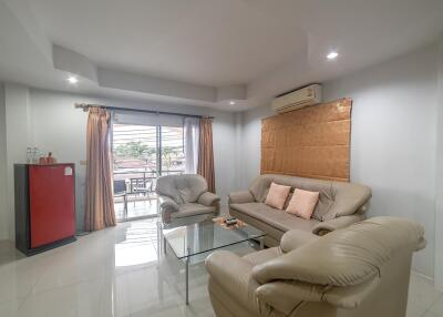 Spacious and well-lit living room with comfortable seating and glass-top coffee table