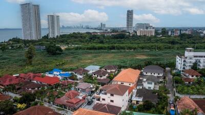 Aerial view of a residential suburb with varied housing and green areas, showcasing the community layout and nearby city skyline