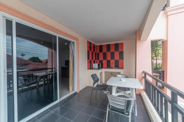 Spacious balcony with monochromatic tile flooring, a modern black and red wall design, and outdoor furniture