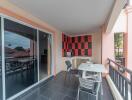 Spacious balcony with monochromatic tile flooring, a modern black and red wall design, and outdoor furniture