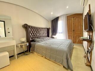 Spacious bedroom with large tufted headboard and attached bathroom