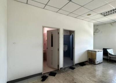 Empty commercial space interior with open door and visible wear
