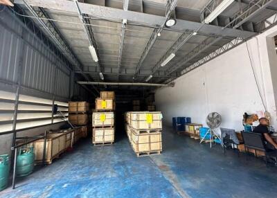 Spacious industrial warehouse interior with storage boxes and a sitting person