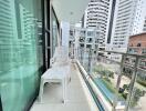 Apartment balcony overlooking a pool with modern white chair and glass safety railing