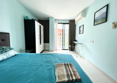 Bright bedroom with queen-sized bed, balcony access, and light blue walls