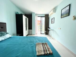 Bright bedroom with queen-sized bed, balcony access, and light blue walls