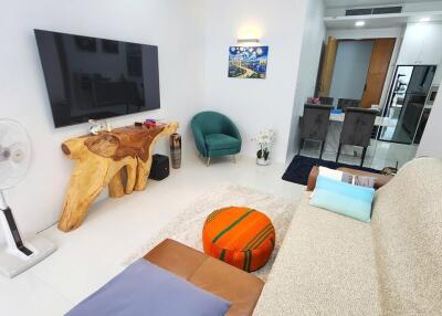 Modern living room interior with a comfortable sofa, television, unique wood coffee table, art, and fan