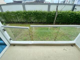 Compact balcony overlooking a green space with glass barriers