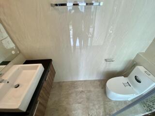 Modern bathroom with beige tiles, sink, and toilet