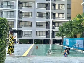 Swimming pool with residents enjoying a sunny day, surrounded by apartment building