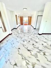 Bright hallway with marble flooring leading towards a room with curtain-drawn windows