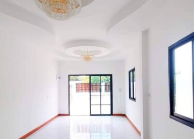 Spacious and bright empty room with white walls, marble flooring, and chandeliers