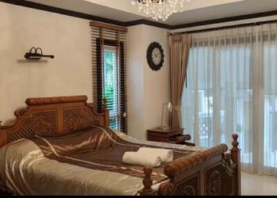 Elegantly decorated master bedroom with wooden furniture and large windows