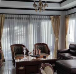 Elegant living room with natural lighting, sophisticated furniture, and chandelier