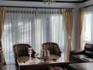 Elegant living room with natural lighting, sophisticated furniture, and chandelier