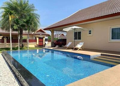 Private swimming pool area with lounge chairs and a tropical garden in a residential property