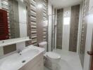 Modern bathroom with tiled walls and floor, including a shower, sink, and toilet
