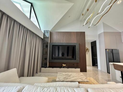 Modern spacious living room with high ceiling and large TV