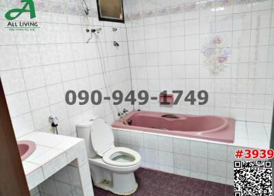 Spacious bathroom with pink fixtures and tiled walls