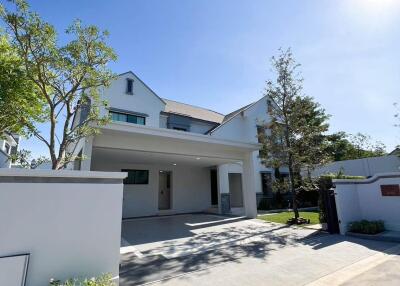 Modern two-story house with a spacious driveway and lush landscaping under a clear blue sky