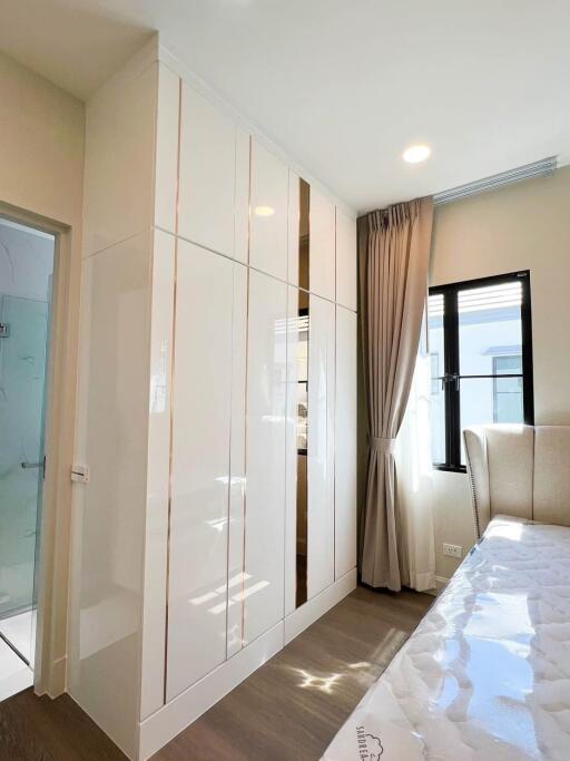 Modern bedroom with built-in wardrobe, glass door, and ample natural light