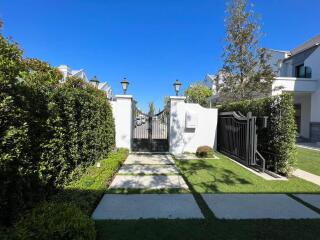 Elegant gated entrance of a residential property with lush greenery