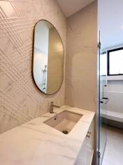 Elegant modern bathroom with textured walls and oval mirror