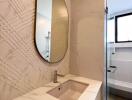 Elegant modern bathroom with textured walls and oval mirror