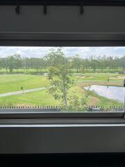 Scenic view from a window overlooking a green landscape with a pond