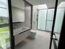 Modern bathroom with large bathtub and glass shower enclosure overlooking greenery