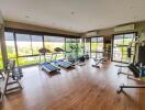 Spacious home gym with various exercise equipment and large windows overlooking nature