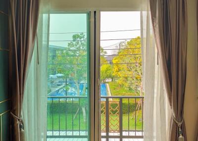 Bright bedroom with floor-to-ceiling glass door leading to balcony