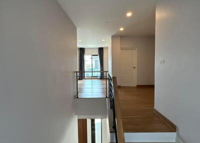 Well-lit interior staircase with wooden steps and modern railing, leading to a bright room