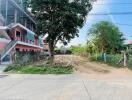 Street view of a building with adjacent vacant land and greenery