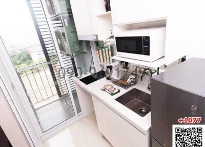 Compact modern kitchen with appliances and city view through balcony door