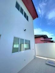 Exterior view of a modern two-story home with white walls and grey tiles under a blue sky