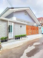 Modern single-story residential home with stone wall facade and wooden gate