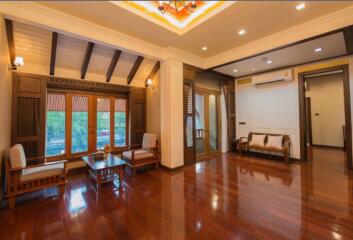 Spacious traditional living room with hardwood floors and wooden ceiling beams