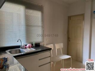 Compact kitchen with sink, window blinds, and seating area