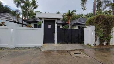 Modern house exterior with a gated entry and lush landscaping