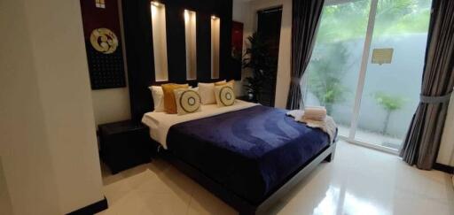 Modern bedroom with a well-dressed bed, decorative lighting, and garden view