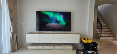 Modern living room with large television and staircase