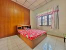 Cozy bedroom with wooden wall paneling and bright window