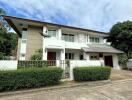 Spacious two-story residential home with white facade, balcony, and garage under a blue sky